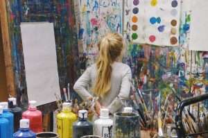 A student paints in a busy studio area