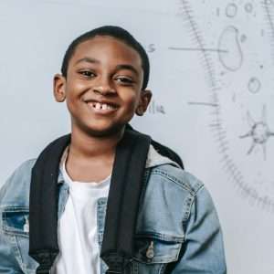 A smiling student stands in front of a whiteboard